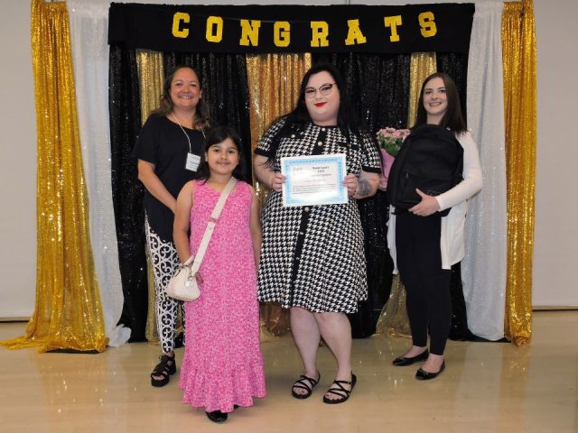 Ashley holding her award beside her daughter and Aunt Leah's staff